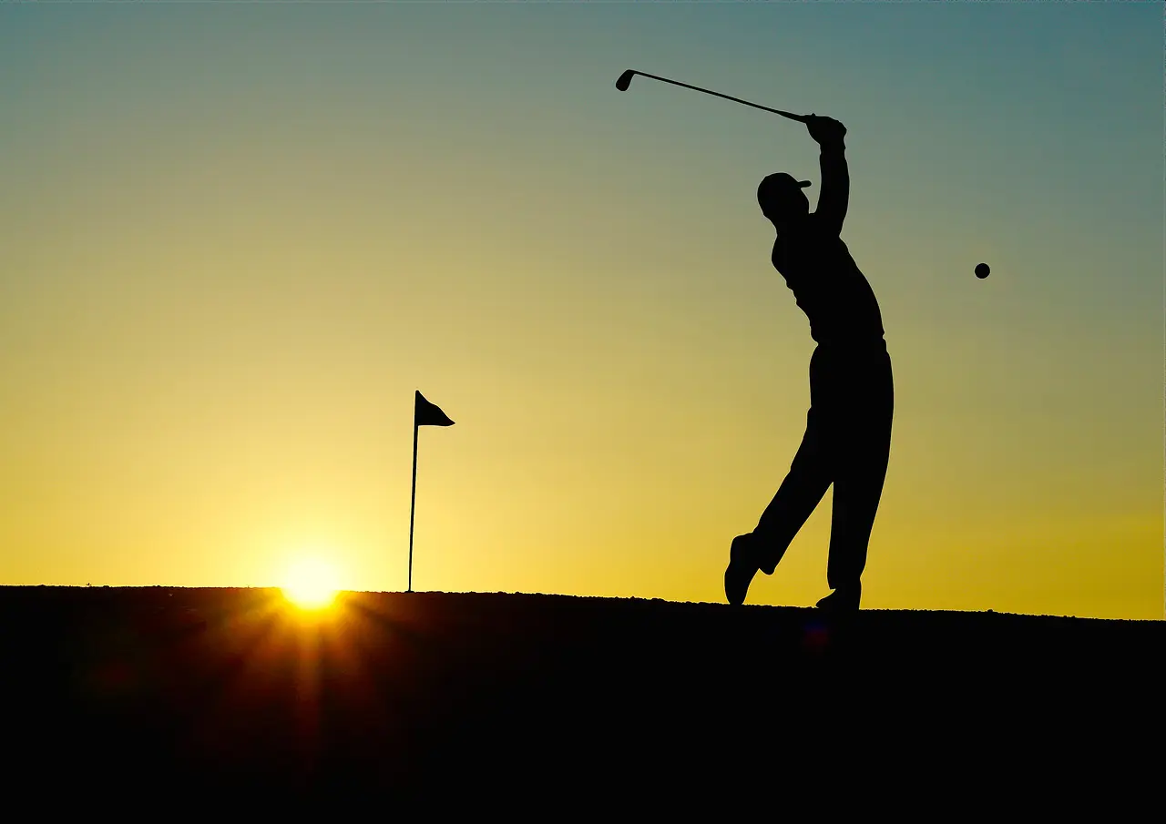 Golfspiller i silhuet ved solopgang
