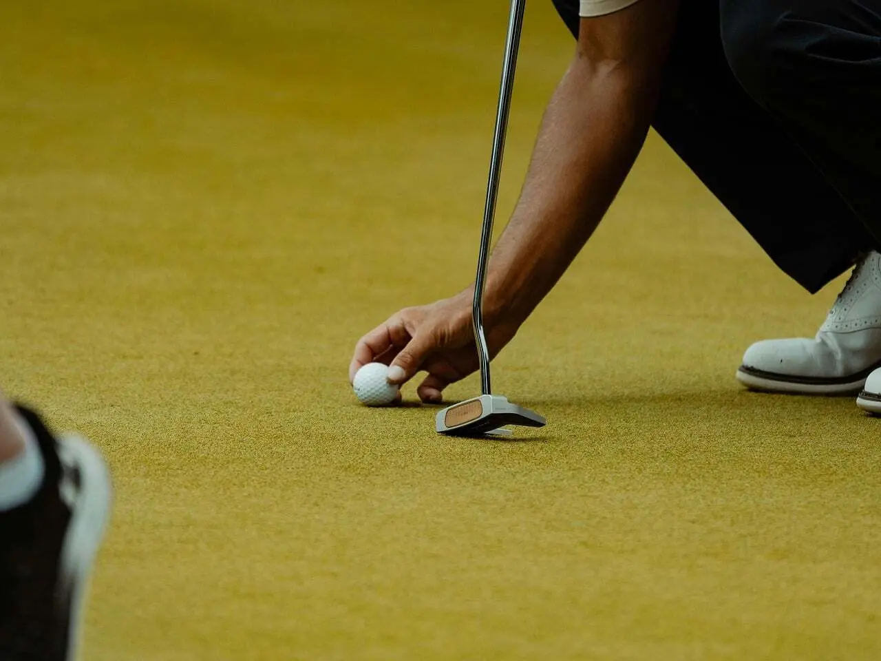 Hånd placerer golfbold ved putter